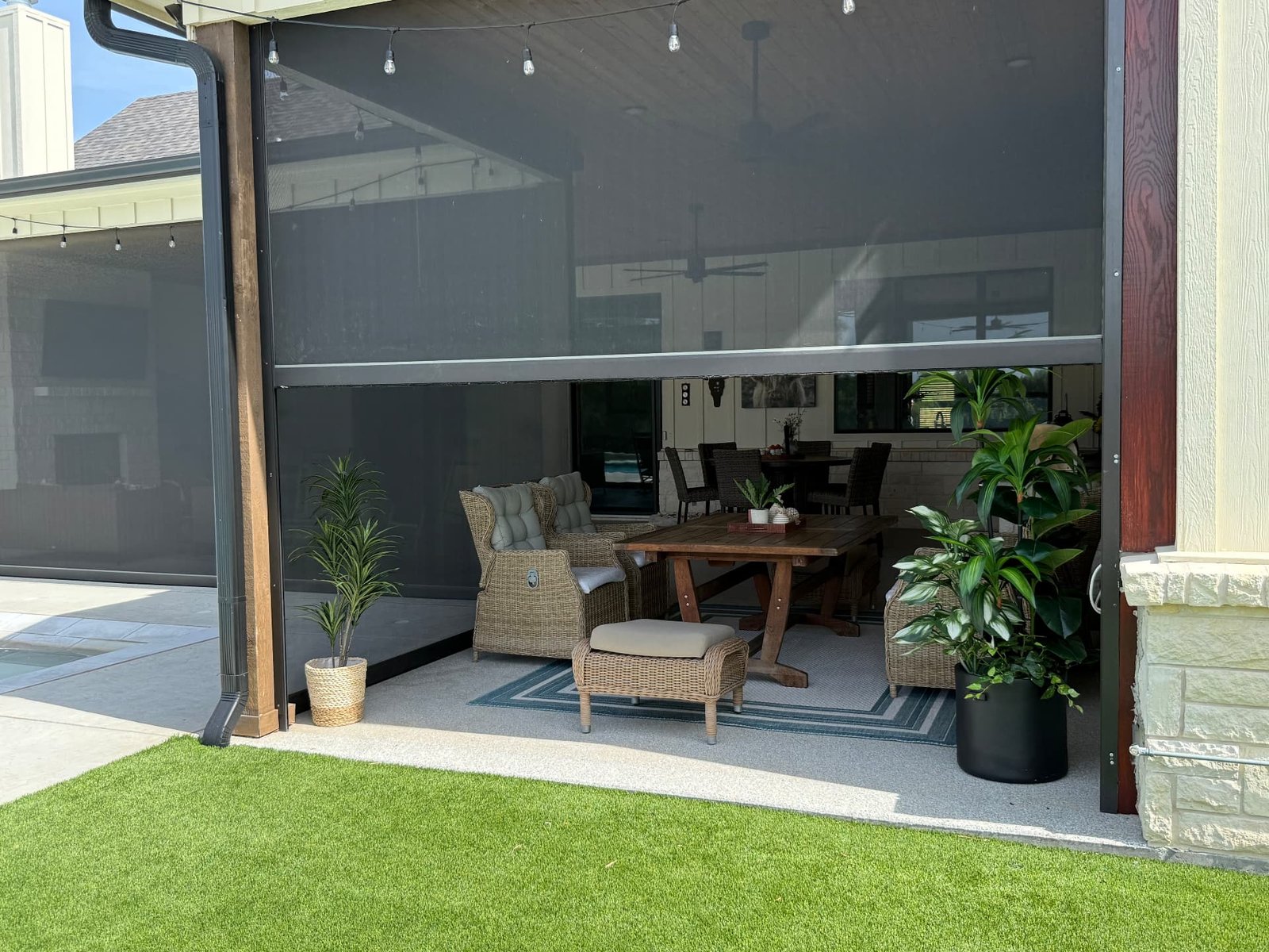 Motorized patio shades partially lowered on a Texas patio, reducing direct sunlight while maintaining the open outdoor view.