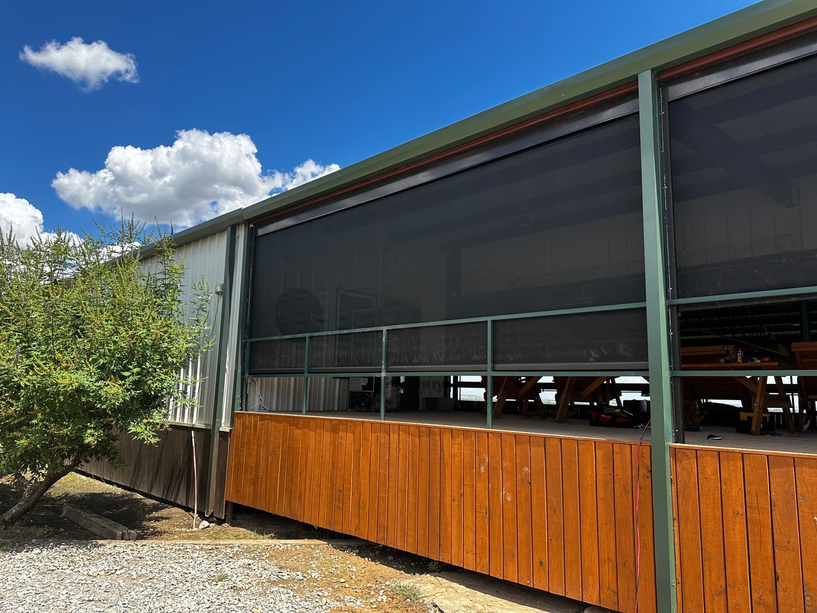 Retractable screens installed on a Texas ranch building with a wooden deck, providing shade, insect protection and a comfortable outdoor area.