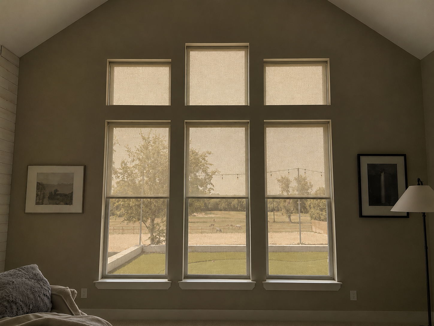 The same bedroom with interior blinds open and solar screens for windows lowered outside the glass. Daylight enters softly, the view remains visible but filtered.