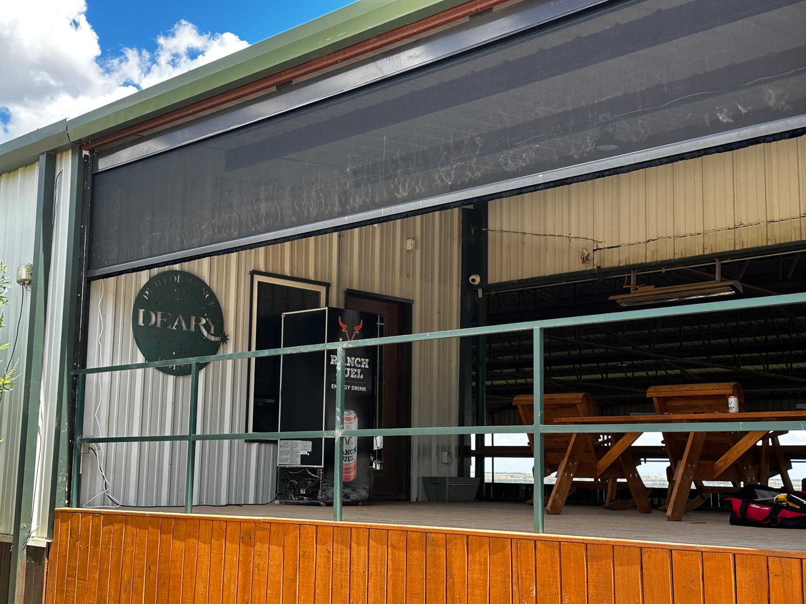Retractable screens spanning a large opening on a Texas ranch building, providing shade and insect protection while maintaining an open view of the property.